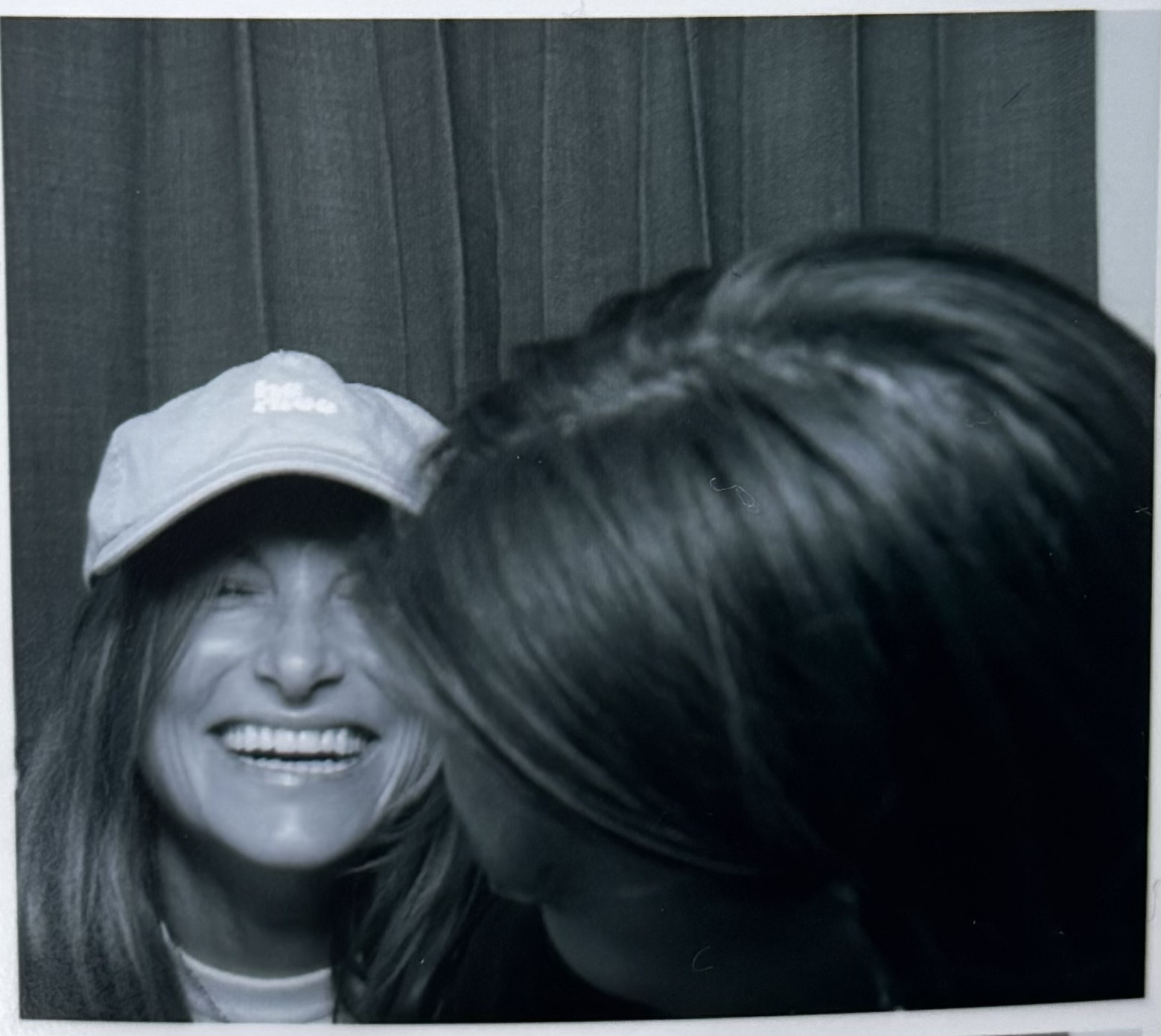 Cécile laughing into the camera while Julia leans in, black-and-white photobooth picture