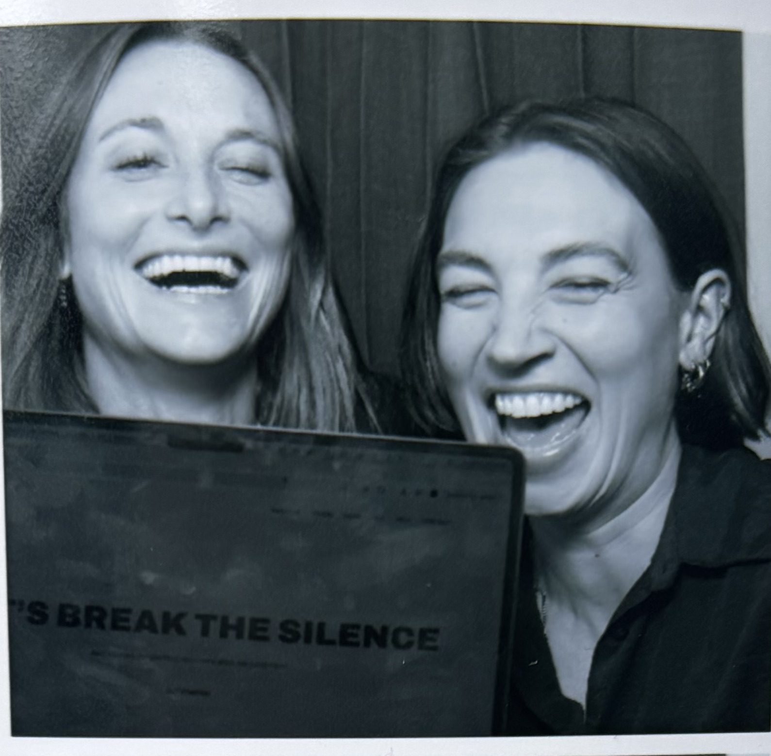 Cécile and Julia laughing behind a laptop showing “Let's break the silence”